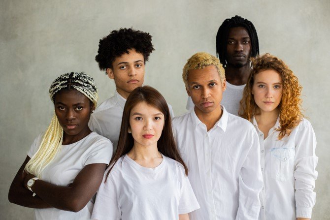 Individuals from different nationalities standing tall, together wearing white shirts showing peace in the world 