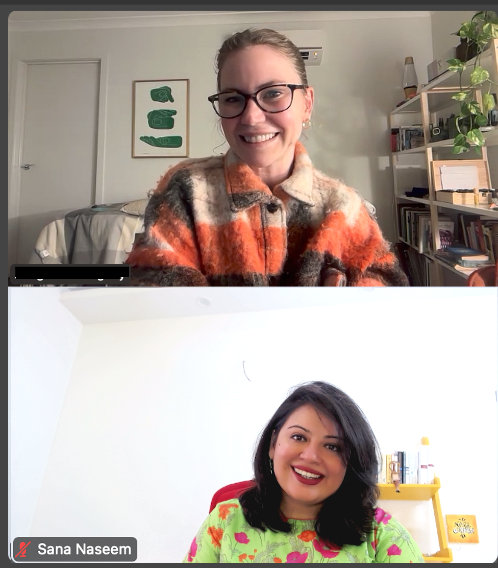 ThetaHealing Dig Deeper Practitioner Training online session with instructor Sana Naseem and student. both smiling women during an online ThetaHealing Dig Deeper Practitioner Training session, one wearing a bright orange and brown checkered jacket and glasses, the other in a green floral top, with bookshelves in the background.